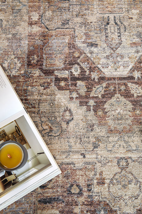 Close-up of a patterned rug with a candle and book on a table.