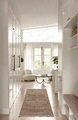 Modern interior of a home with white walls, glass doors, and a runner on the floor.