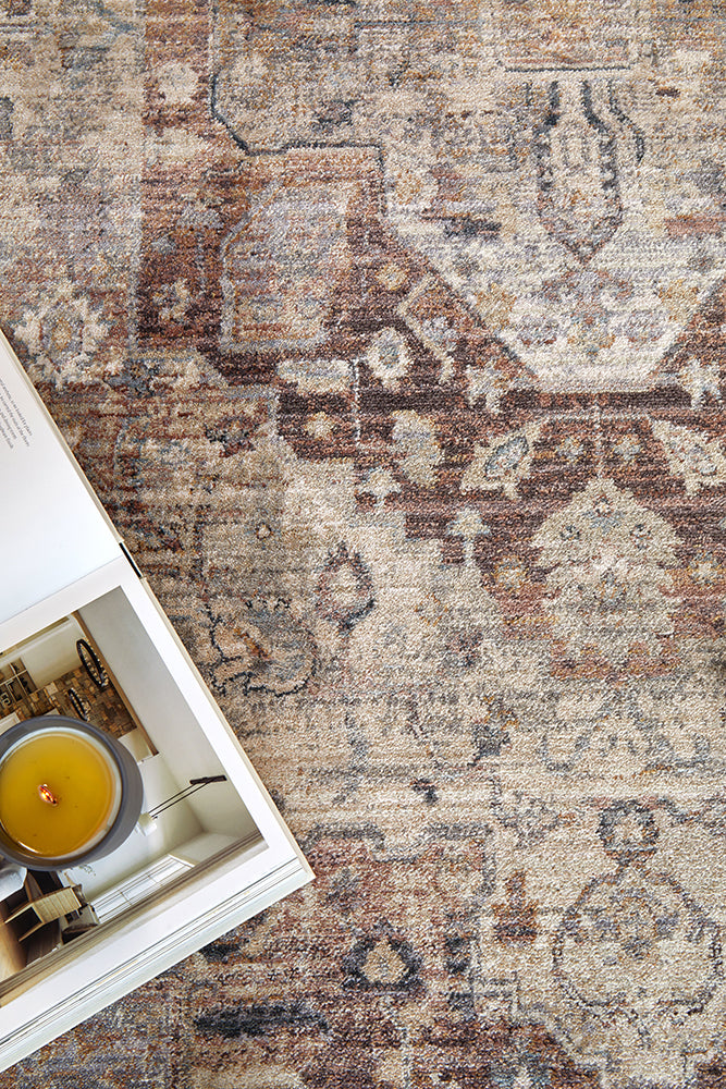 Close-up of a patterned rug with a candle and book on a table.